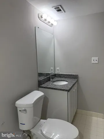 a bathroom with a granite countertop toilet sink and mirror