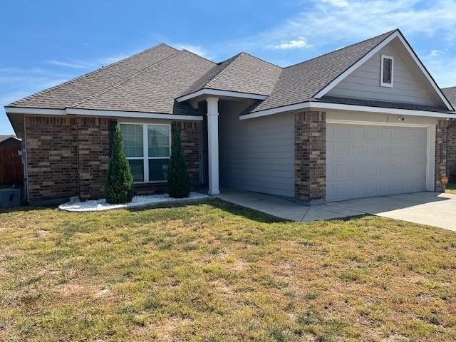 4013 Bravo Ranch Road Waco, TX 76705 - Photo 2 of 33 Ranch-style house with brick siding, a front lawn, driveway, an attached garage, and roof with shingles