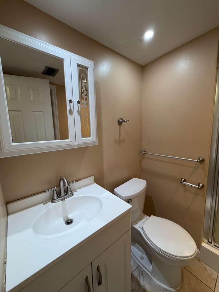 9273 Southwest 8th Street, Unit 209 Boca Raton, FL 33428 - Photo 5 of 9 a bathroom with a toilet sink and mirror