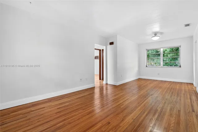 a view of empty room with wooden floor and window