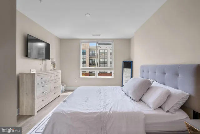 a bedroom with a bed and a flat screen tv in white walls