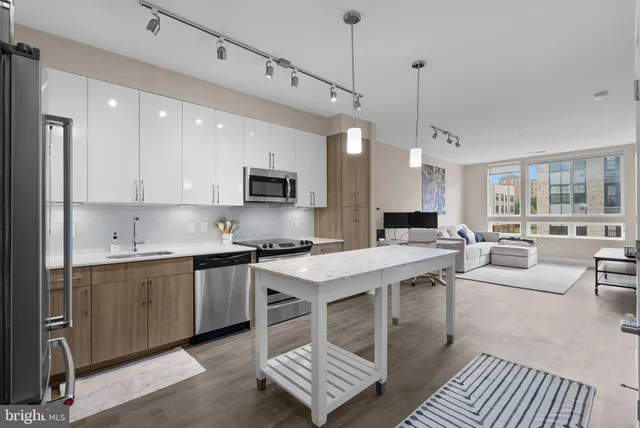 a open kitchen with stainless steel appliances granite countertop a stove top oven a sink dishwasher a dining table and chairs with wooden floor