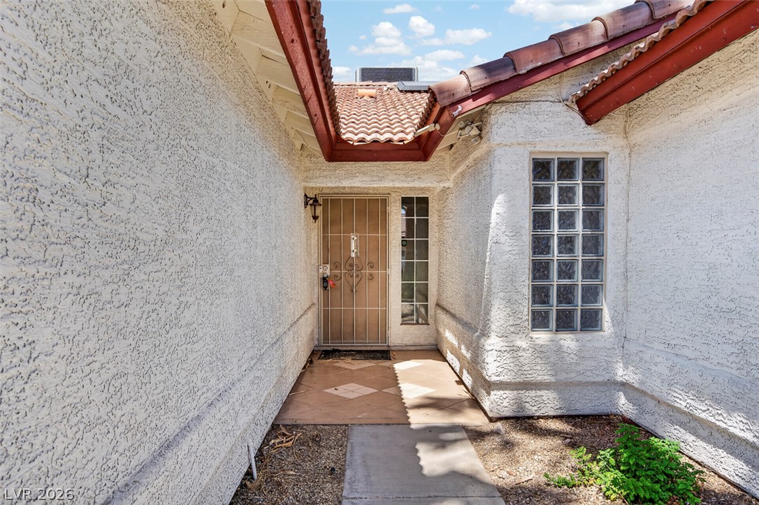 2609 Shakespeare Road Las Vegas, NV 89108 - Photo 3 of 41 A terracotta-tiled roof crowns this stucco-finished entrance, featuring a secure wrought iron gate.