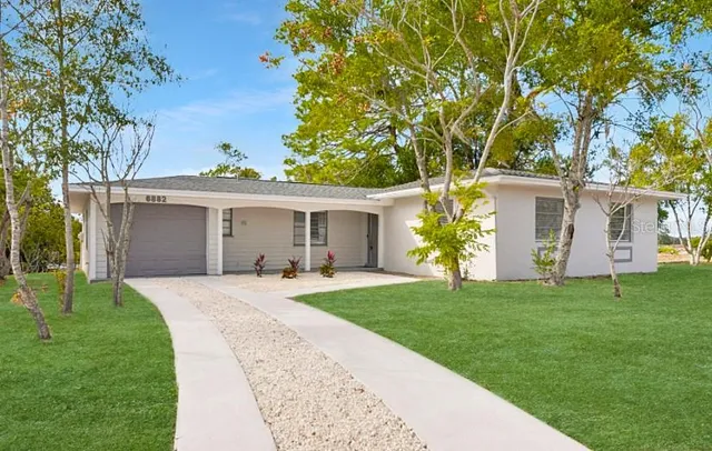 a front view of a house with a garden and trees