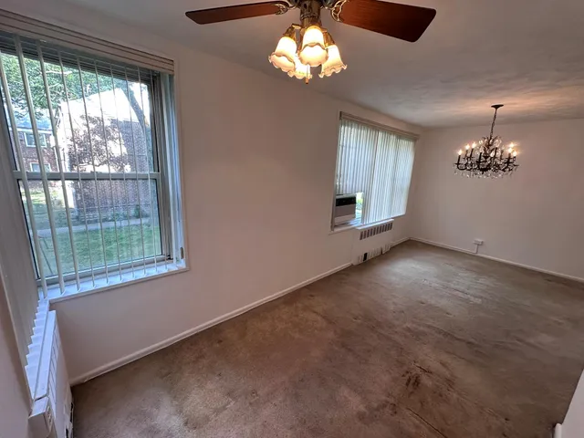 a view of a livingroom with a chandelier fan and windows