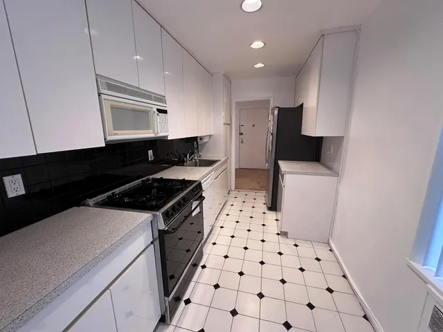 a kitchen with granite countertop a stove a sink and a refrigerator