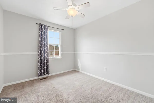 an empty room with windows and chandelier fan
