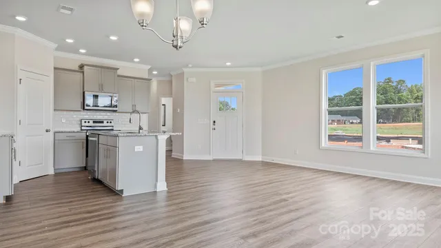 a view of kitchen with stainless steel appliances granite countertop a stove top oven a sink and a refrigerator