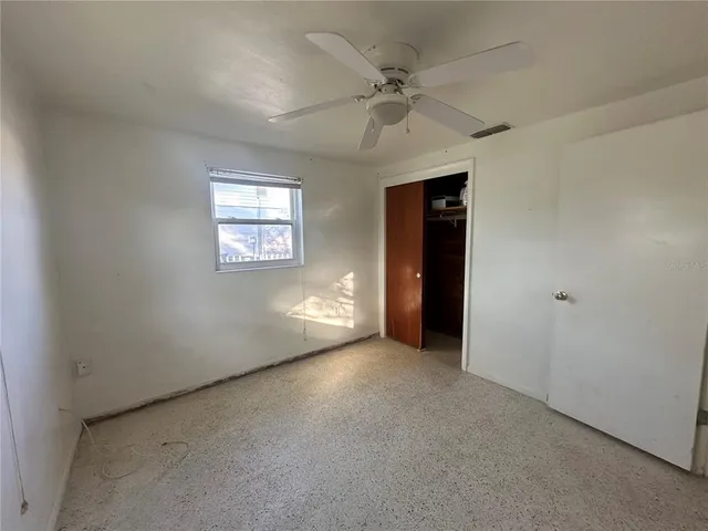 an empty room with windows and fan