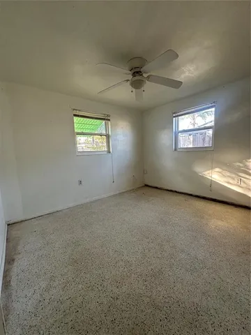an empty room with windows and ceiling fan