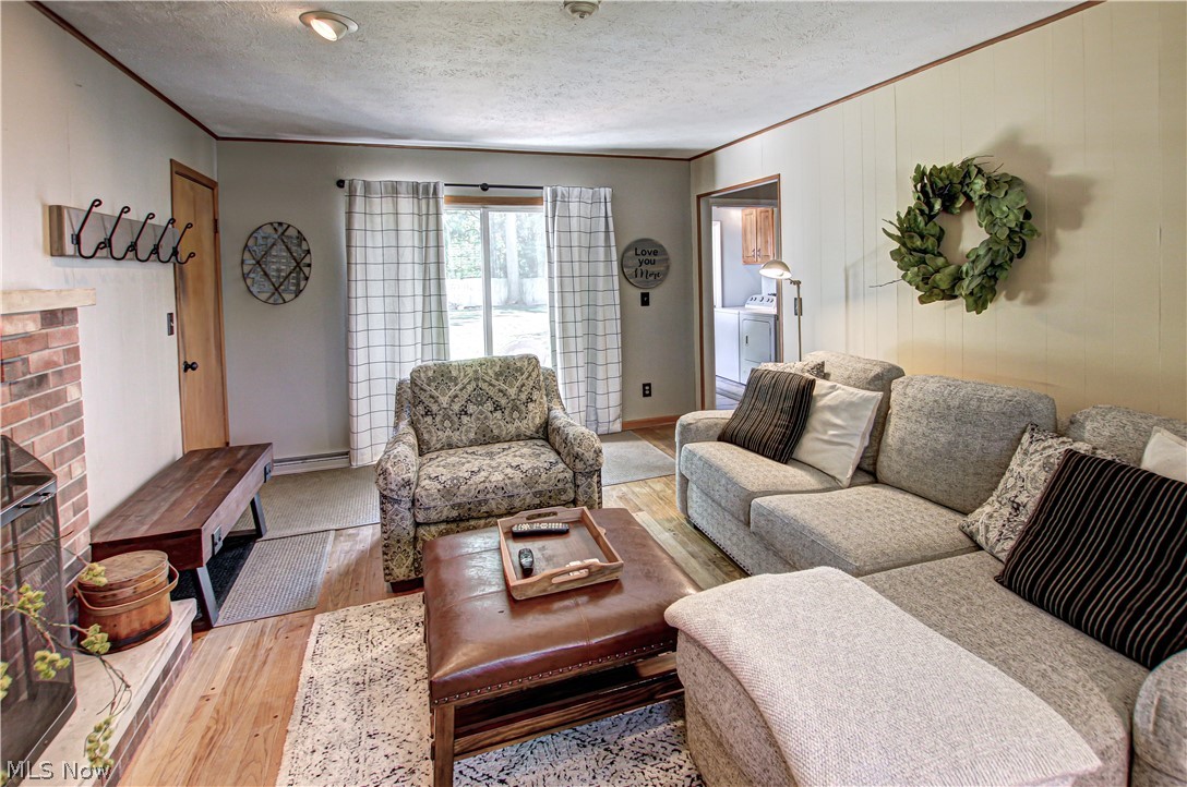 910 Andrews Road Medina, OH 44256 - Photo 19 of 45 Family room featuring a brick fireplace, wood-type flooring, a textured ceiling, and crown molding