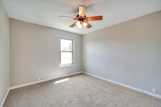an empty room with a window and a ceiling fan