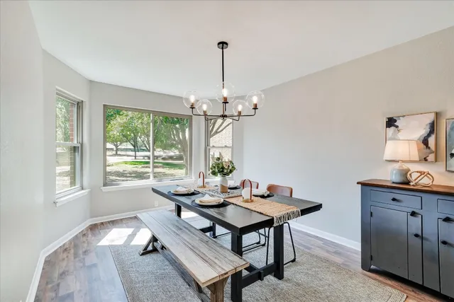 a dining room with wooden floor a chandelier a wooden table and chairs