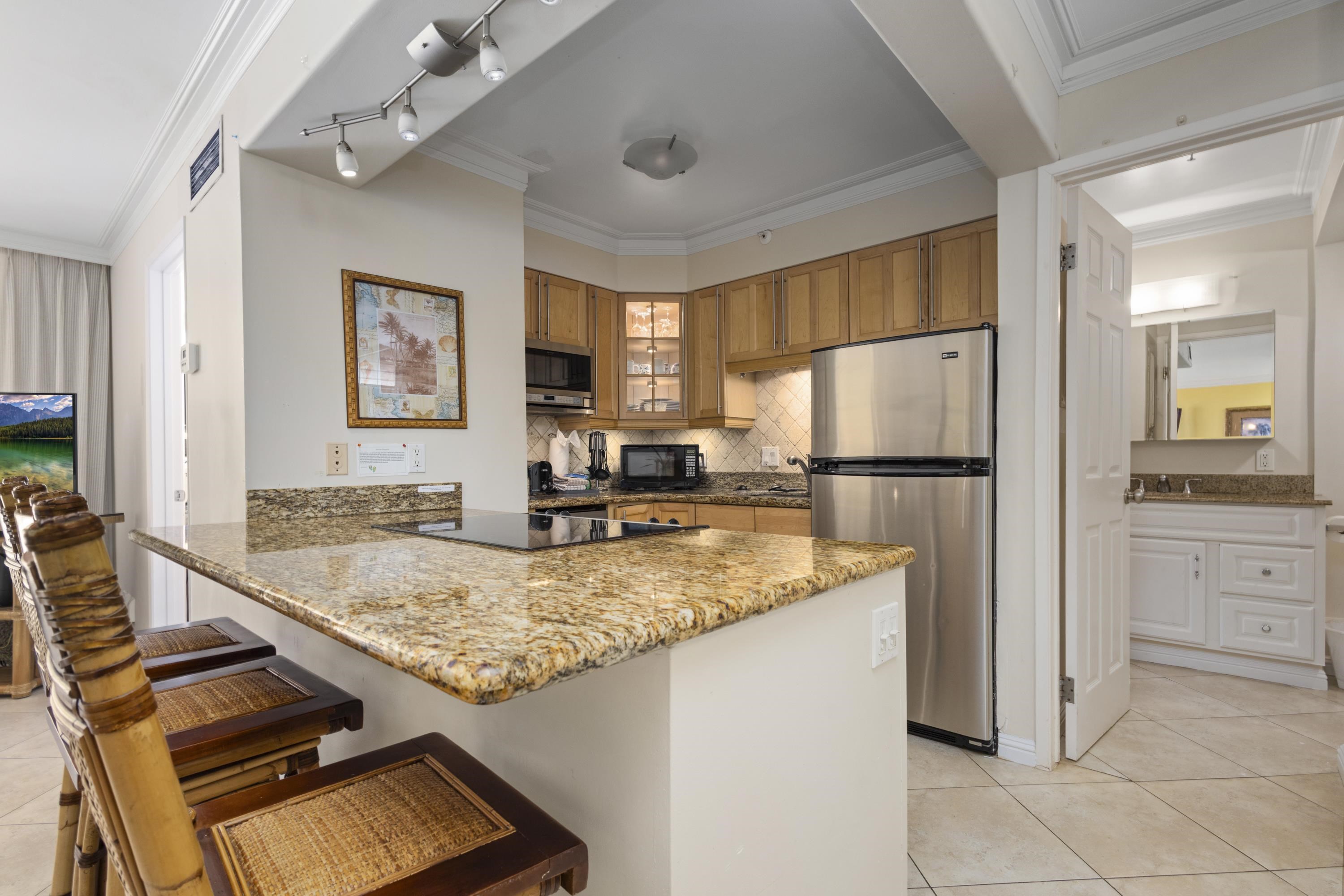 4365 Lower Honoapiilani Road, Unit 115 Lahaina, HI 96761 - Photo 4 of 44 a kitchen with kitchen island granite countertop a sink appliances counter top space and living room view