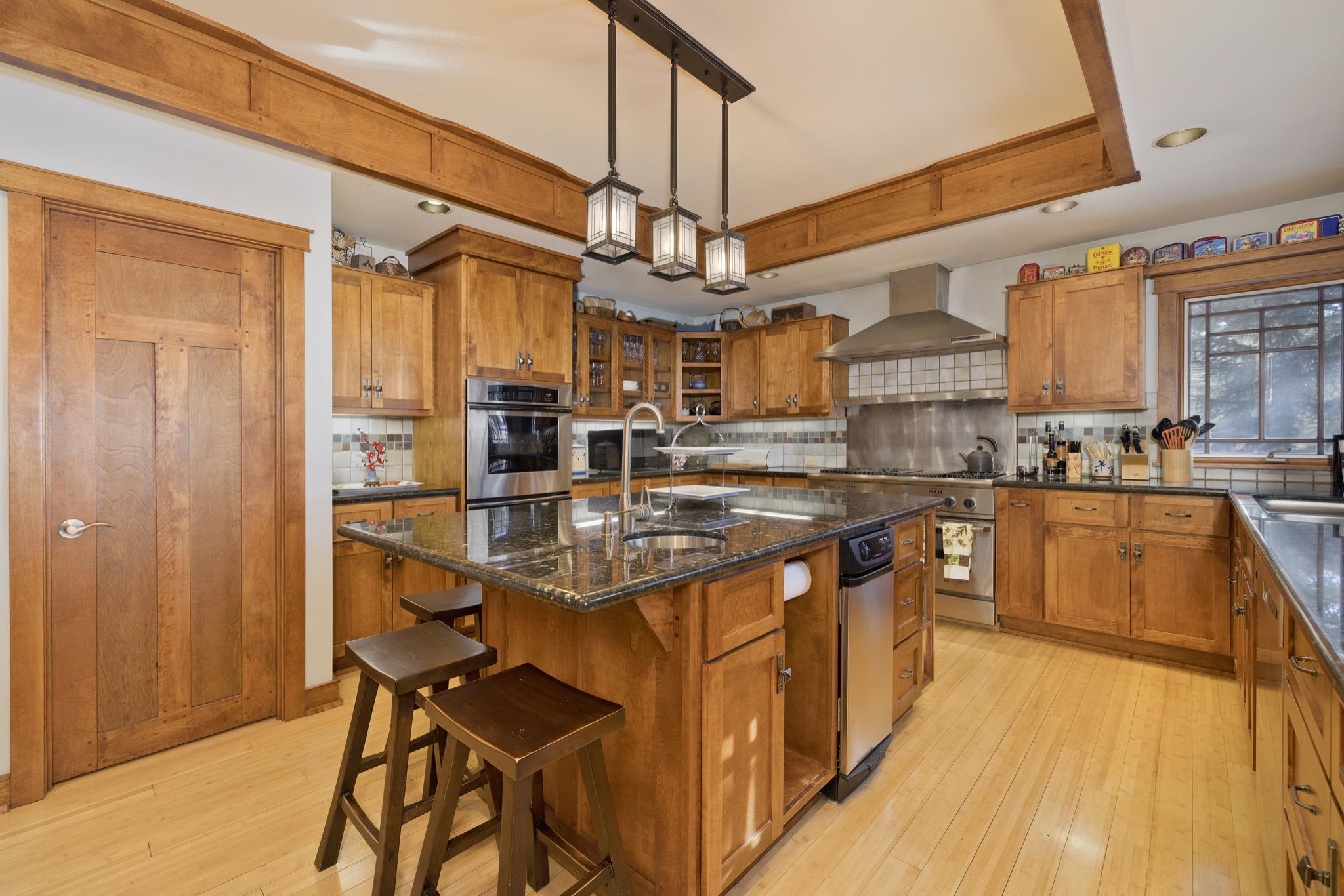 56 Wagon Road Mammoth Lakes, CA 93546 - Photo 10 of 56 Kitchen with brown cabinets, pendant lighting, an island with sink, a breakfast bar area, and recessed lighting