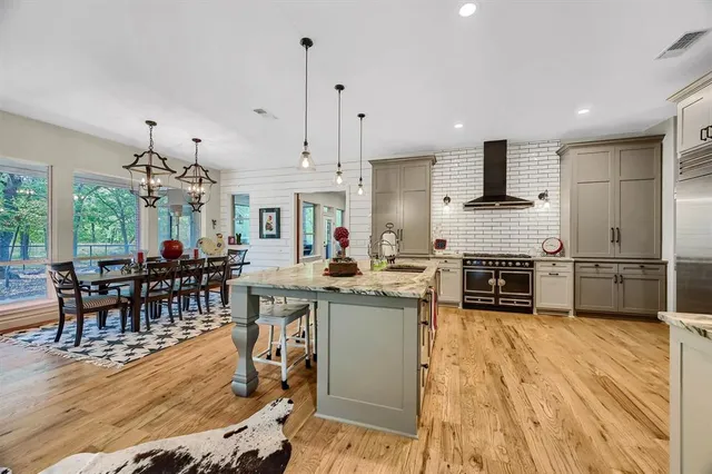 a kitchen with stainless steel appliances granite countertop a stove top oven a sink dishwasher a dining table and chairs with wooden floor