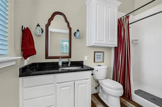 a bathroom with a granite countertop sink and a toilet