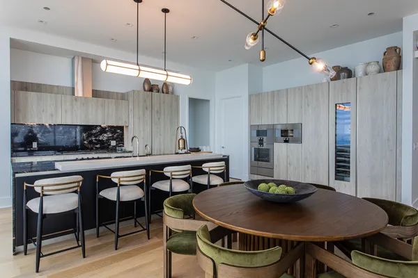a kitchen with stainless steel appliances granite countertop a dining table chairs and white cabinets