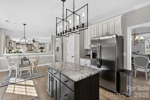 a kitchen with stainless steel appliances granite countertop a kitchen island a stove a refrigerator a sink and a dining table