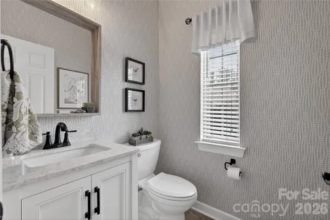 a bathroom with a toilet a sink a mirror and a window