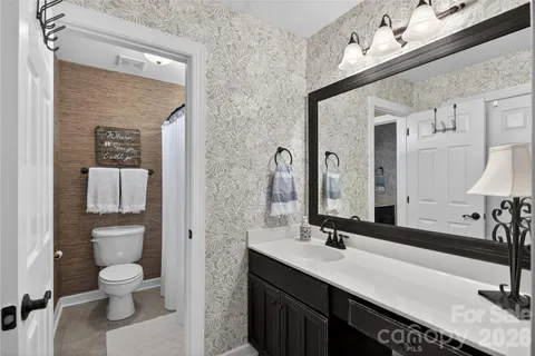 a bathroom with a granite countertop sink a toilet and a mirror