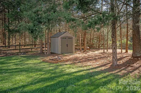 a view of a backyard with large trees and wooden fence