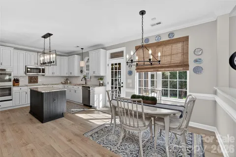 a kitchen with granite countertop a stove a sink a dining table and chairs