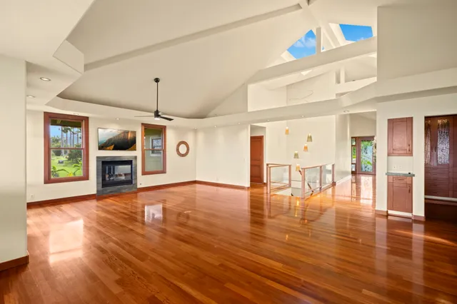 a view of an empty room with wooden floor fireplace and a window