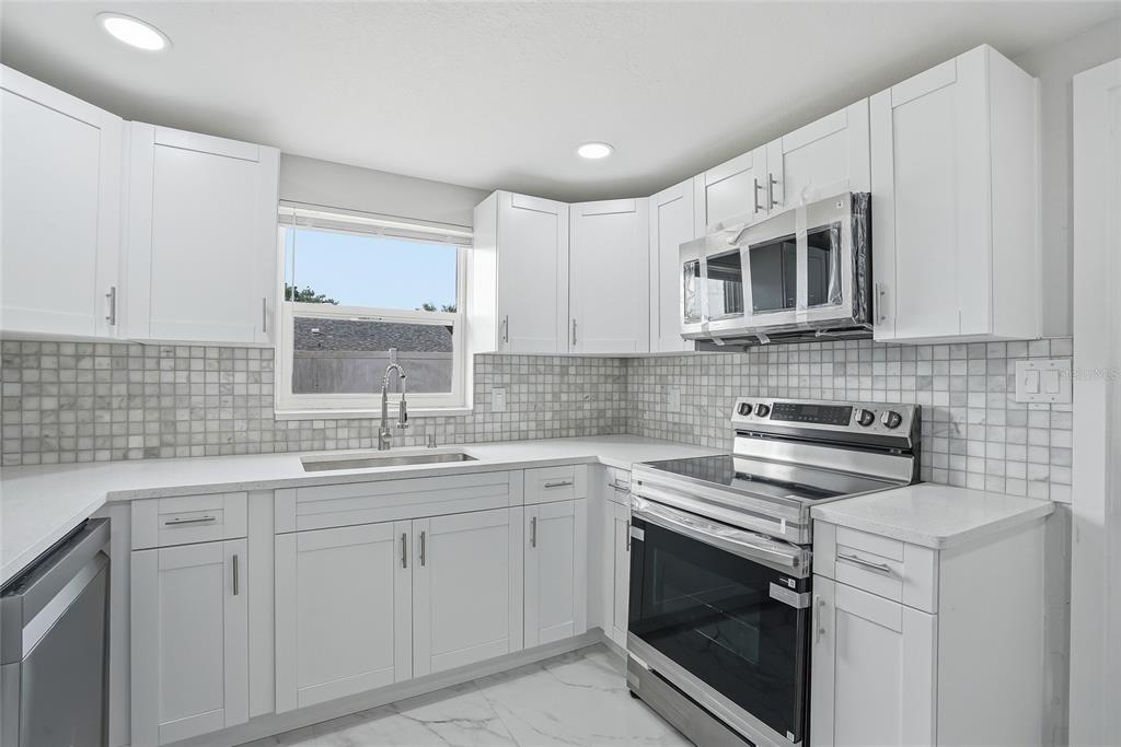 6302 Diamond Drive New Port Richey, FL 34653 - Photo 13 of 43 a kitchen with white cabinets stainless steel appliances and sink