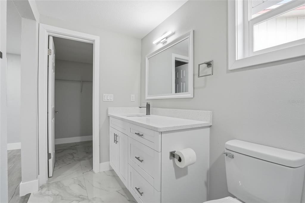 6302 Diamond Drive New Port Richey, FL 34653 - Photo 20 of 43 a bathroom with a granite countertop sink a toilet and a mirror