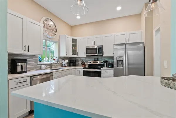 a kitchen with stainless steel appliances granite countertop a refrigerator a stove and a sink