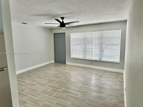 an empty room with windows and fan