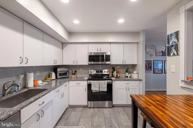 a kitchen with stainless steel appliances granite countertop a stove top oven a sink dishwasher and cabinets with wooden floor