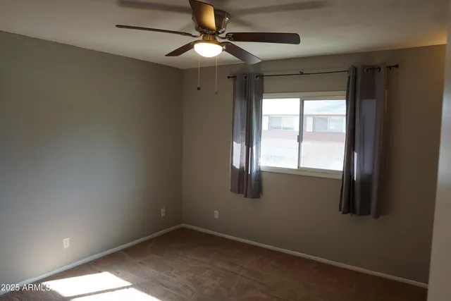an empty room with windows and fan