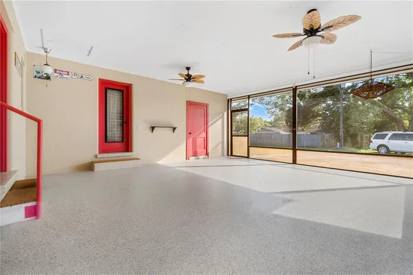 a view of an empty room with wooden floor and a ceiling fan