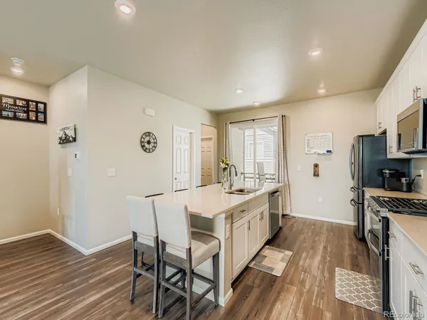 a large kitchen with stainless steel appliances a large counter top and wooden floors