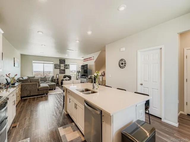 a open kitchen with stainless steel appliances kitchen island a white cabinets and couches