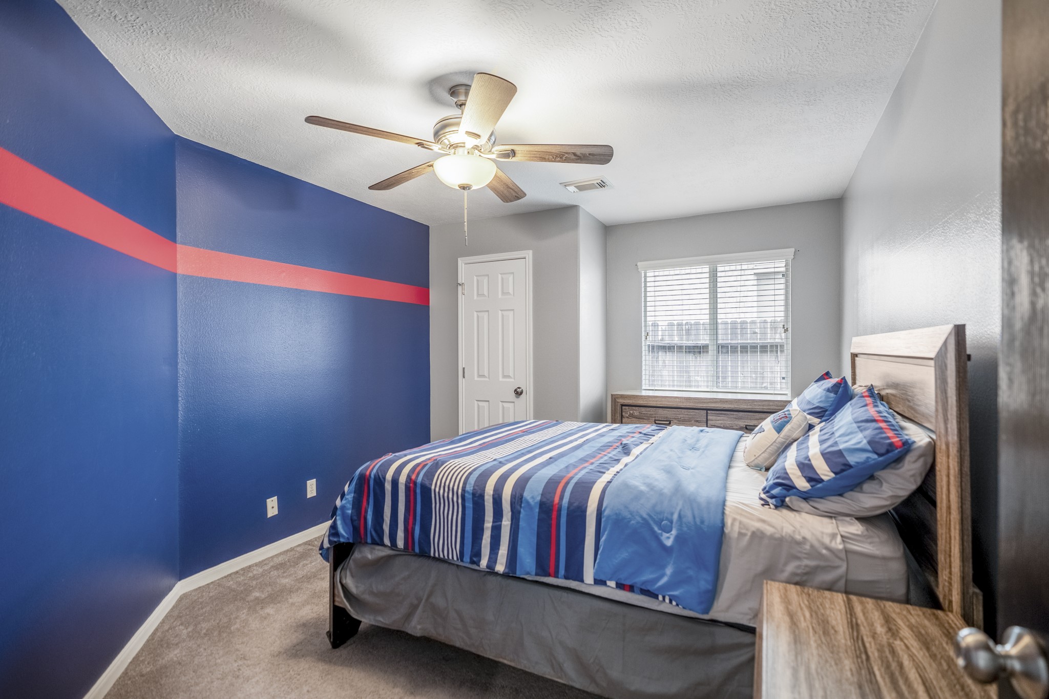 3411 Utah Beach Court Spring, TX 77388 - Photo 31 of 50 This fourth bedroom brings personality with bold accent walls, a ceiling fan, and natural light from the window. The closet sits just inside the room, and its location near the nearby hall bath keeps the secondary bedroom spaces easy to access from the main flow of the home.