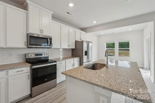 a kitchen with granite countertop a sink stove and refrigerator