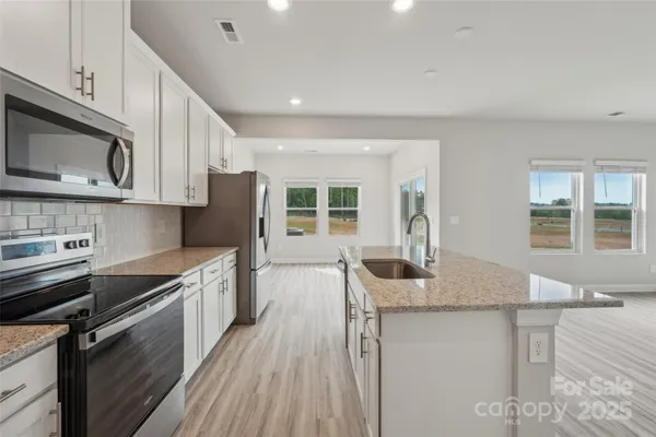 a kitchen with stainless steel appliances granite countertop a sink stove and microwave