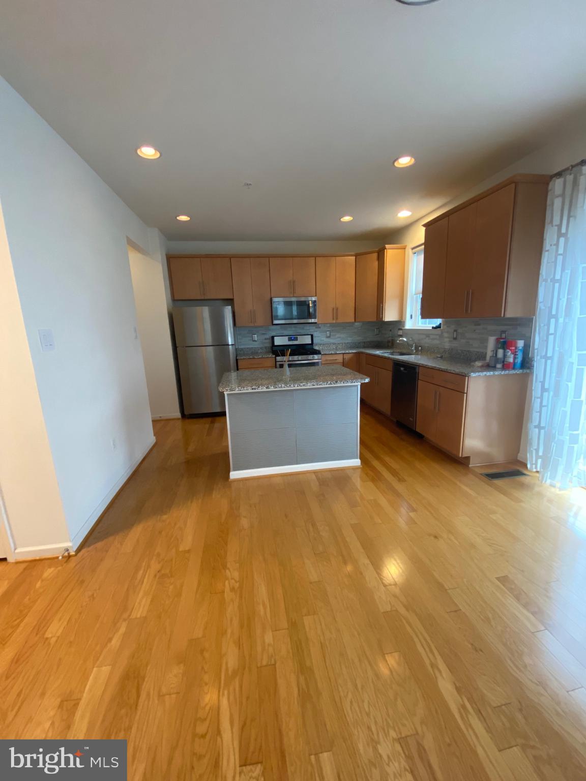 918 Ramble Run Road Baltimore, MD 21220 - Photo 3 of 23 a view of a kitchen with kitchen island a sink wooden floor and a counter top space