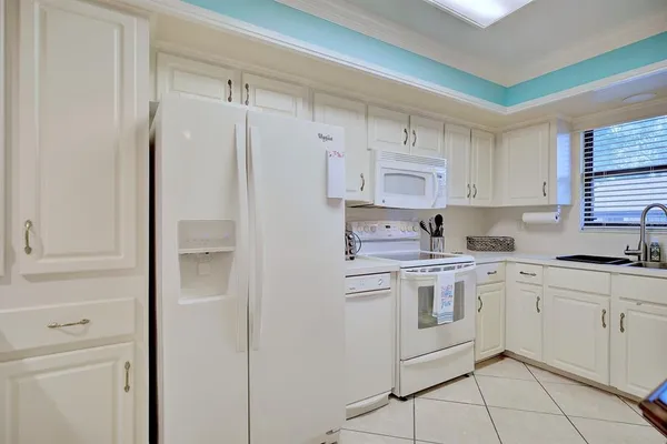 a kitchen with white cabinets and white appliances