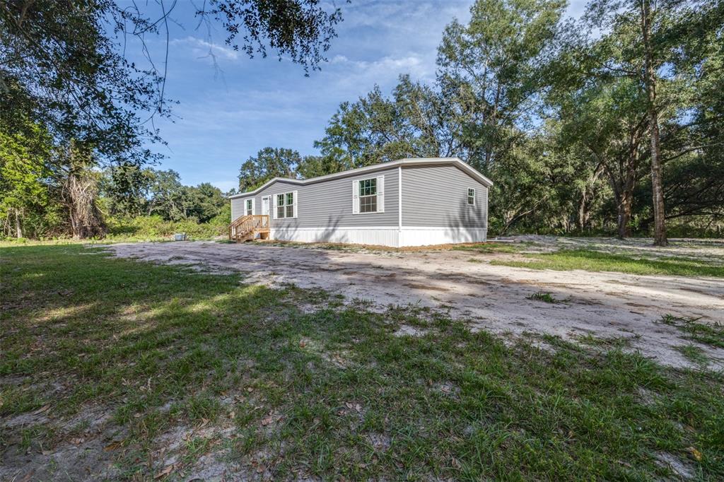 892 Southwest 124th Lane Webster, FL 33597 - Photo 2 of 29 a view of a yard in front of a house with large trees