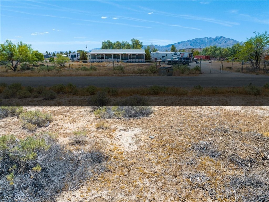 4580 Lawrence Road Pahrump, NV 89048 - Photo 10 of 40 Frontage view of a spacious desert property with distant mountains under a broad blue sky.