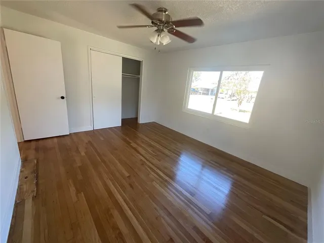 a view of an empty room with a window and wooden floor