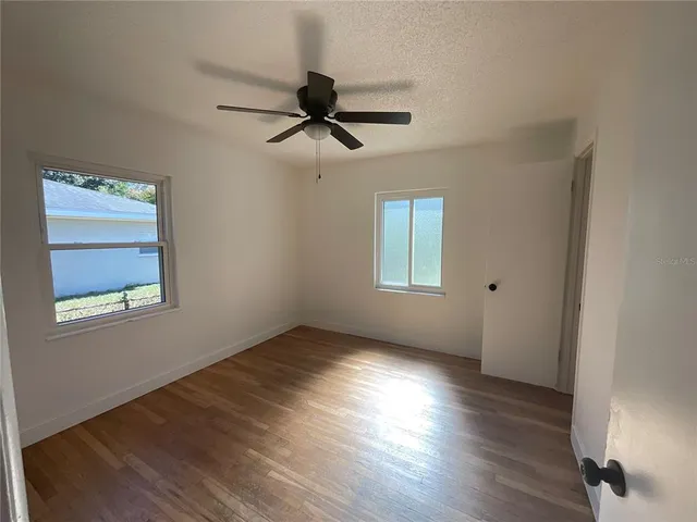 a view of empty room with wooden floor and fan