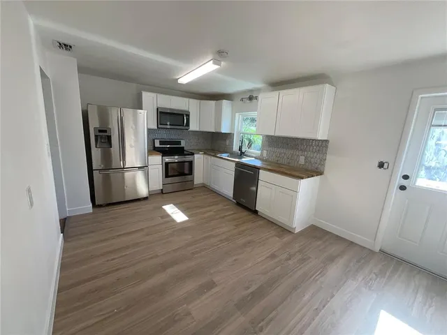 a kitchen with wooden floors and stainless steel appliances