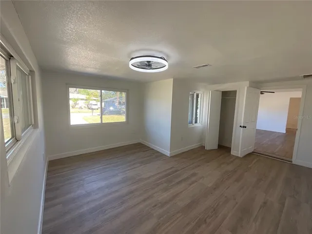 an empty room with wooden floor and windows