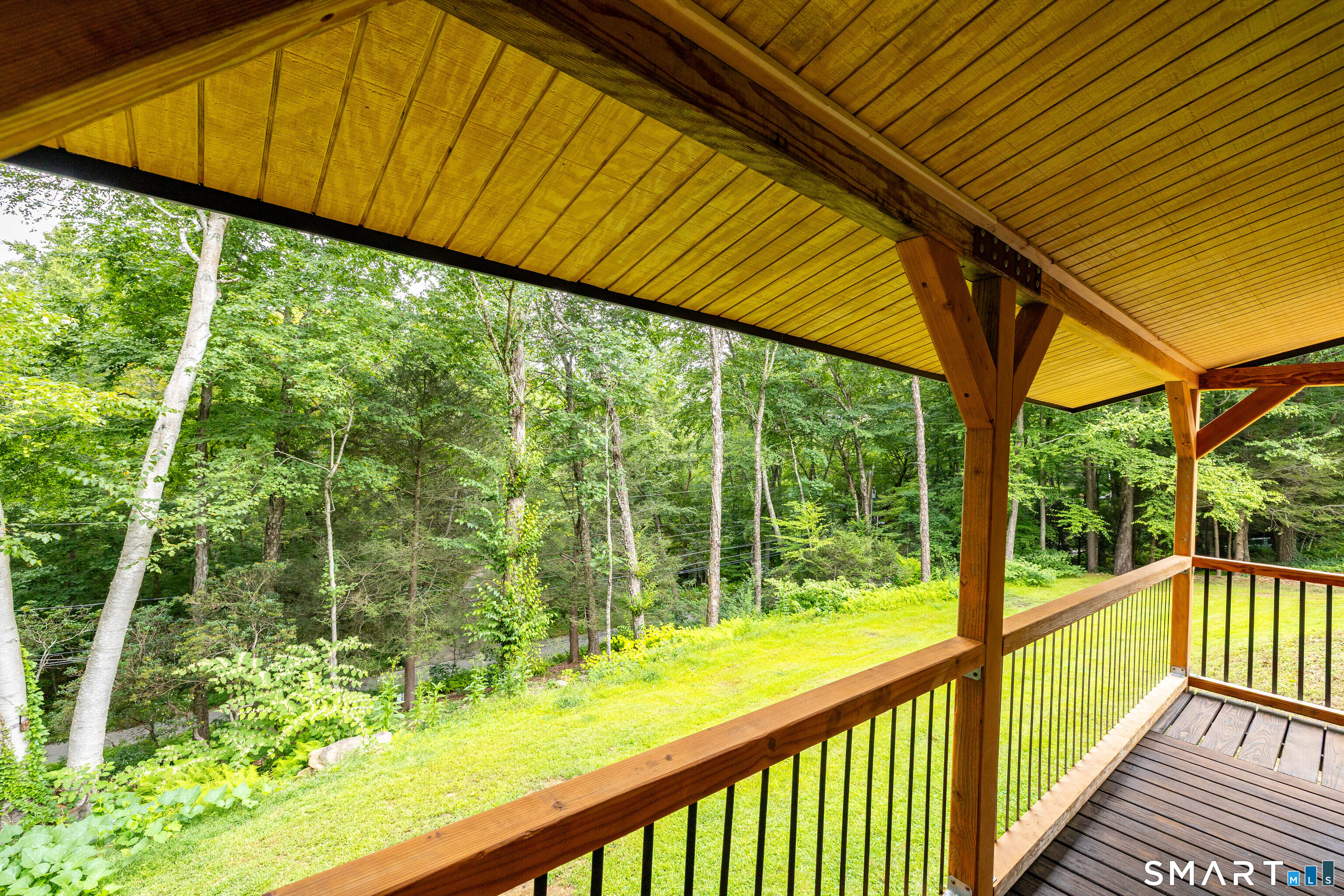 1386 Cedar Swamp Road Coventry, CT 06238 - Photo 6 of 39 Relax and take in the natural surroundings from the wrap-around porch, showcasing beautiful cedar beams and decorative gussets overlooking the peaceful, tree-lined lawn and surrounding landscape.