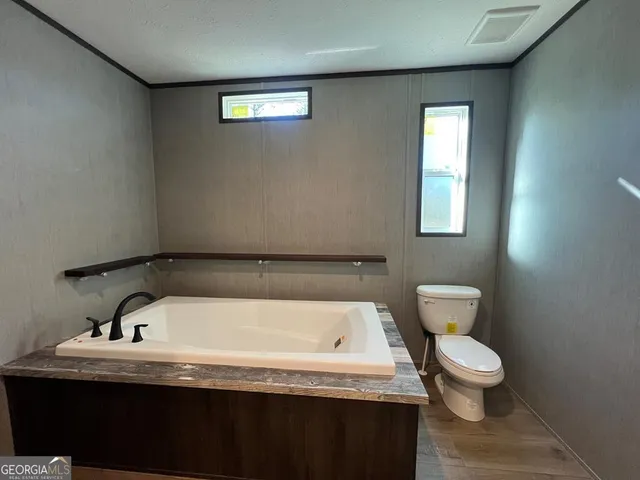 a bathroom with a granite countertop sink a toilet and a window